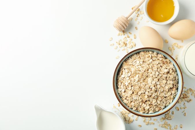 Composition with oatmeal flakes on plain background, top view. Cooking breakfast