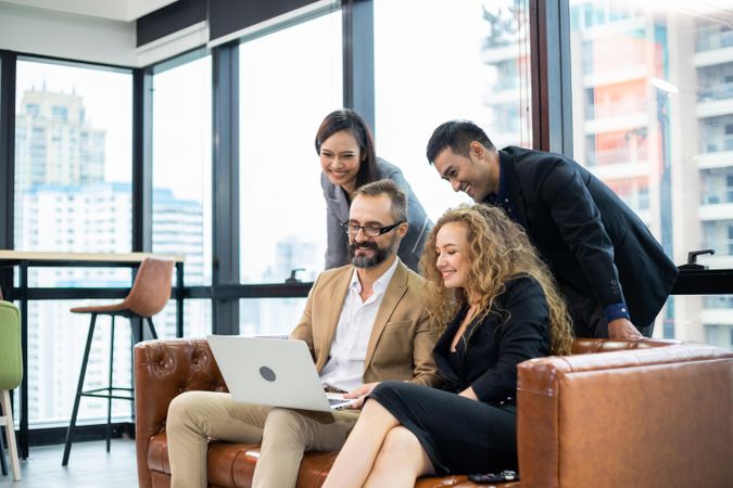 Smiling business people watching project on computer and brainstorming in modern office