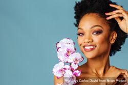 Studio beauty shot of a smiling Black woman with purple flowers 5okLk5