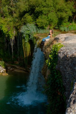 Young woman sitting near waterfall