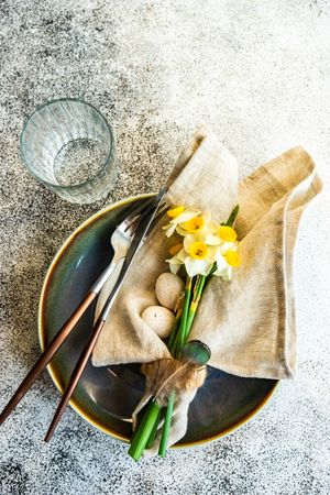 Minimalistic table setting for easter with daffodil and eggs on plate