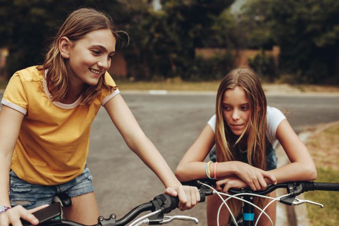 Two cheerful girls riding bicycles outdoors