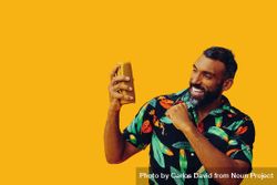 Black male in bold patterned shirt and small speaker in yellow room 5zqYk0