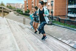 Young women friends training running up stairs in town