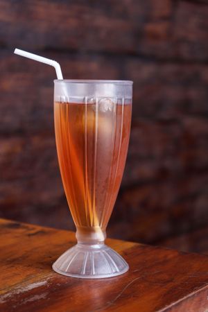 Es Teh Manis, a Glass of Cold Ice Tea with White Plastic Straw