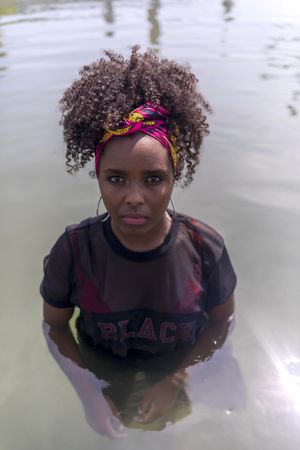 Beautiful Black woman with headscarf in water and looking at camera