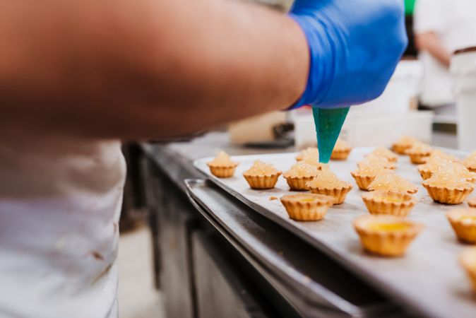 Crop baker squeezing dough on tray