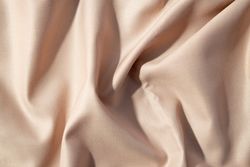 Close up silk shiny light brown fabric background texture.