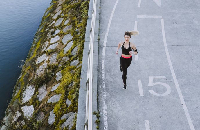 Woman running on embankment near water