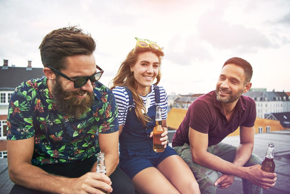 Group of happy people with beer on a roof