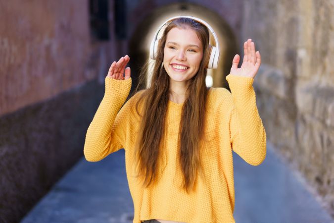 A Cheerful Young Woman is Dancing Joyfully in a Colorful Street While Wearing Headphones