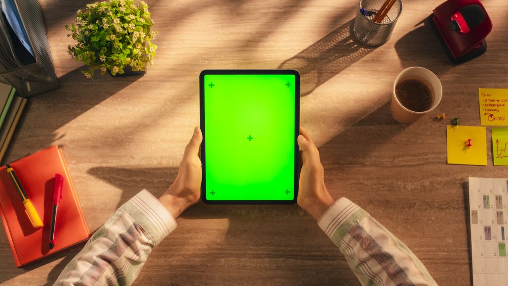 Marketing Manager Checking Social Network Posts on a Tablet Computer with Mock Up Green Screen Vertical Display. Top Down View Concept for Online Communication, Internet Branding, Business Promotions