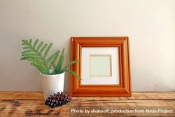 Square wooden picture frame on wooden desk with branch and pinecone mockup 5qwmpb