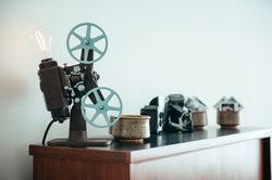 Vintage film projector with a lightbulb sitting on shelf with photo cameras