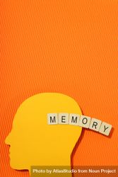 Orange duotone flat lay of head with the word “memory” in wooden blocks, vertical 56qlx0