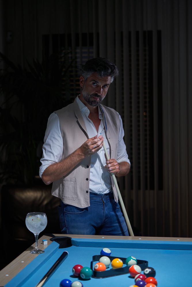 Adult male applying chalk on billiard cue stick