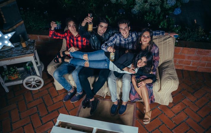 Woman lying over her friends' lap while sitting on a coach at a party
