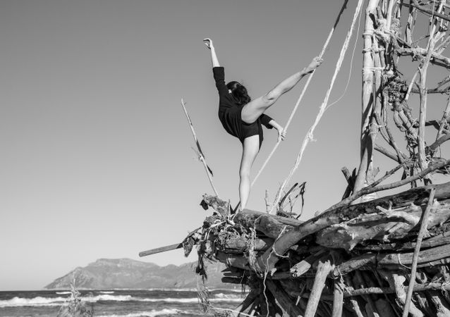 Young woman with upped leg on decorative wooden ship near water on shore