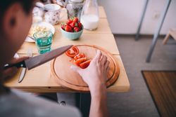Man slicing tomatoes on wooden cutting board
