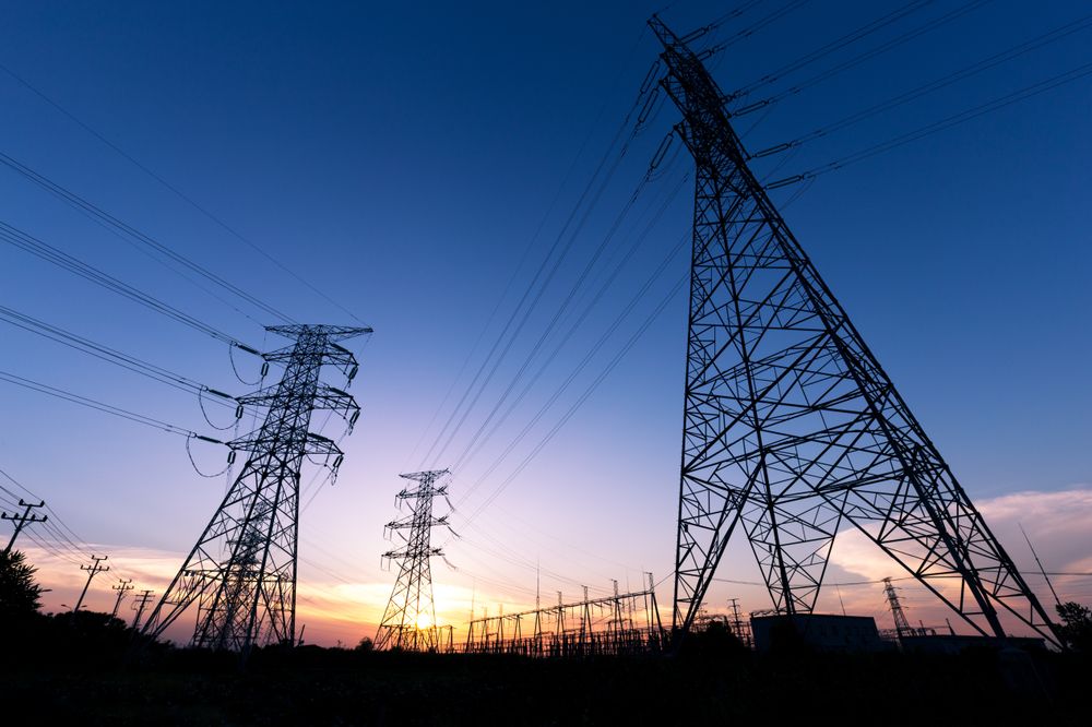 Silhouetted Power Lines Against Vibrant Sunset Sky with Transmission Towers