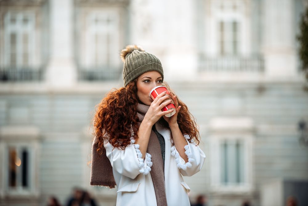 Woman drinking coffee wandering in the streets of Madrid on winter