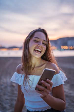 Cheerful young woman using smartphone on resort