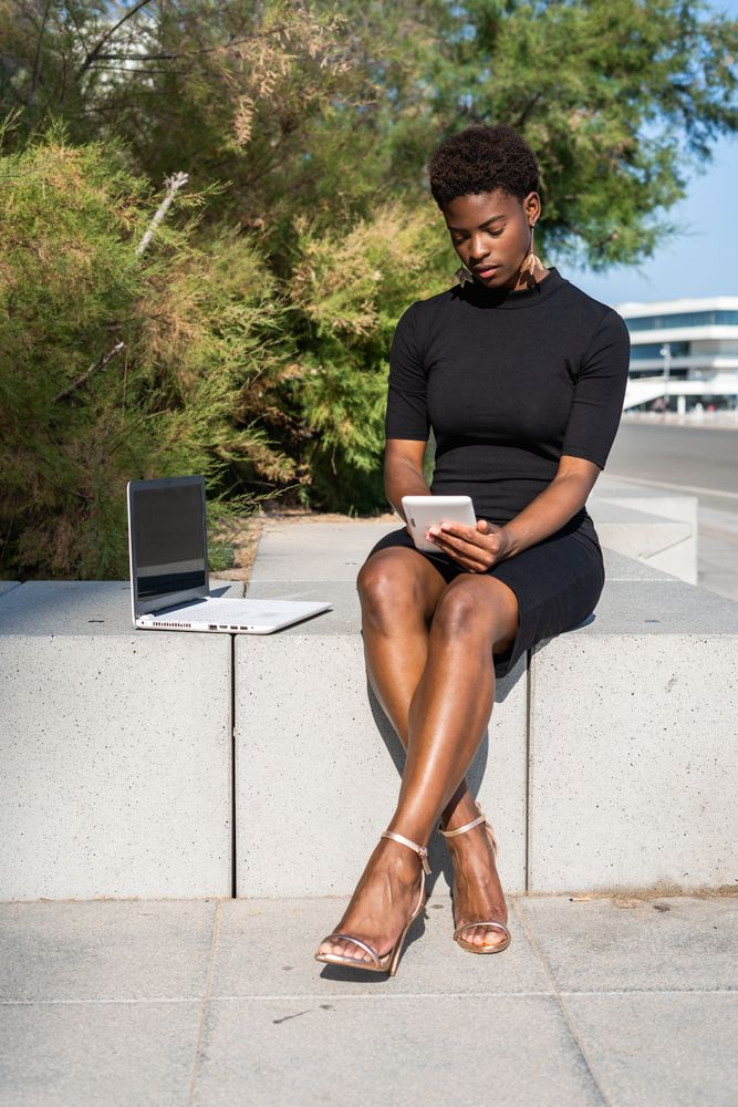 Serious female surfing laptop near modern building