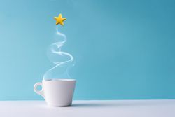 Christmas tree made of steaming coffee or hot drink with yellow star cookie