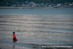 Girl in red dress wading in seashore water bekKN5