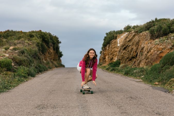 Smiling woman riding longboard on asphalt road