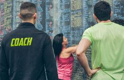 Trainer supervising female athlete writing down results on the gym board