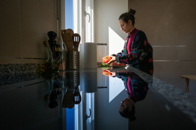 Woman washing tomato over sink