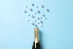 Champagne bottle and glitter on blue background, space for text
