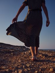 Crop woman walking on stony coast