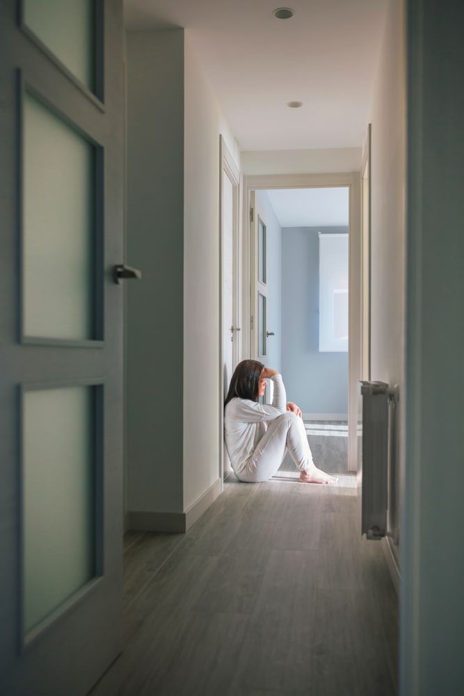 Woman in pajamas sitting on the floor of a mental health center
