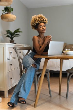 Black woman with laptop sitting on chair during breakfast