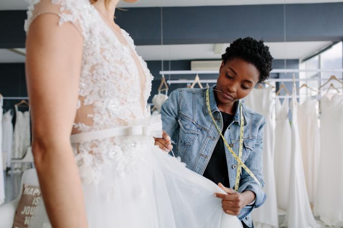 Woman making adjustments to bridal gown in her boutique