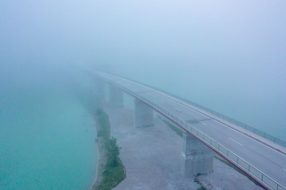 Aerial view image in the morning with Sylvenstein Bridge covered in fog