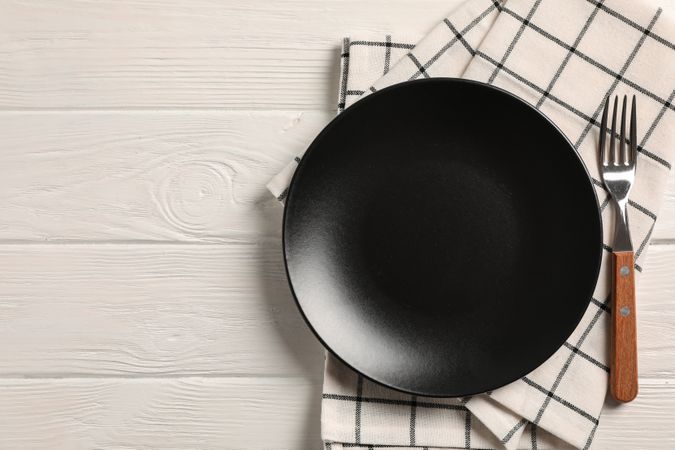 Kitchen towel with cutlery on wooden background, top view
