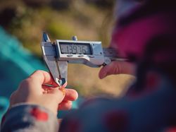 Crop preteen girl looking at data of digital caliper