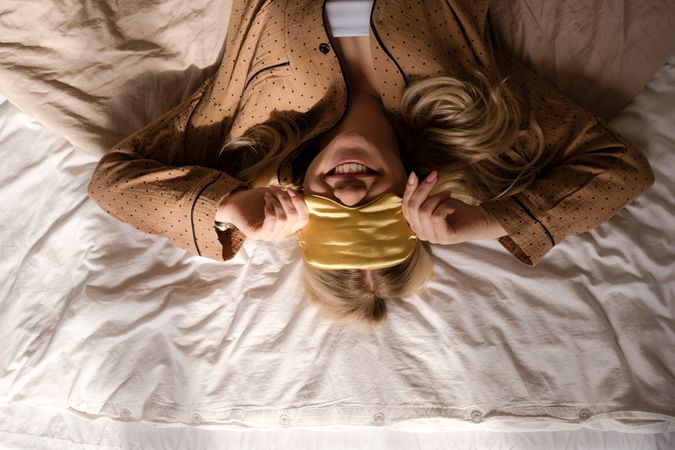 Playful woman smiling on bed with headband.