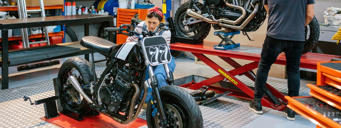 Mechanic repairing custom motorcycle on factory