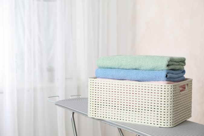 Basket with clean laundry on ironing board, space for text