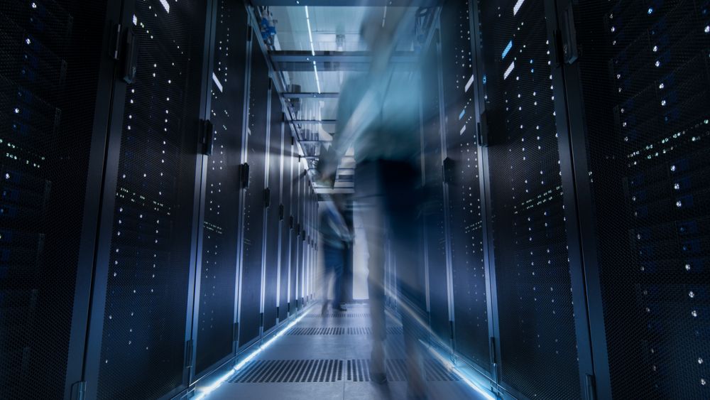 Shot of Corridor in Large Data Center Full of Moving and Working People.