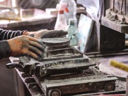 Crop craftsman pouring dry clay into mold while creating tile