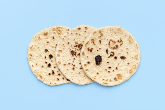 Three Indian flatbreads on a blue background, above view