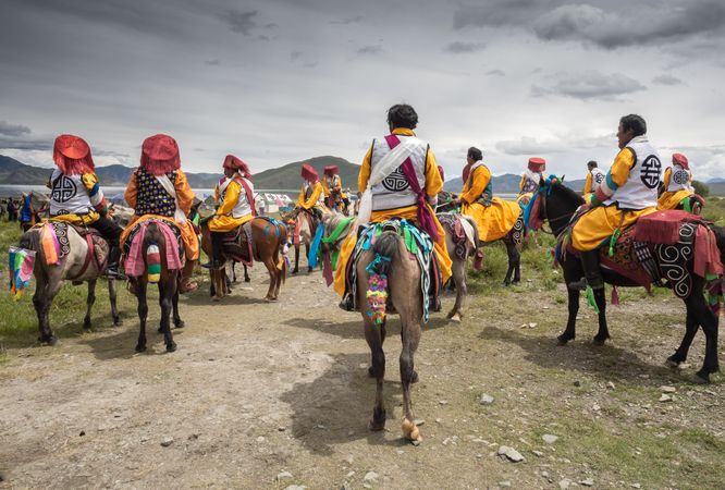 Tibet - August, 29 2014: Anonymous men riding horses on cloudy day