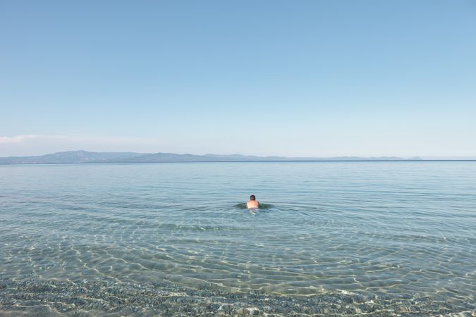 Man swimming in clear water in sunlight