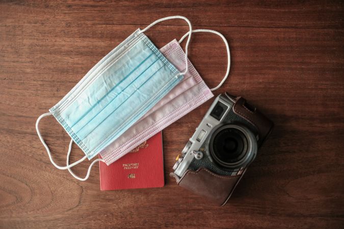 Overhead shot of facemasks, passport and camera on table