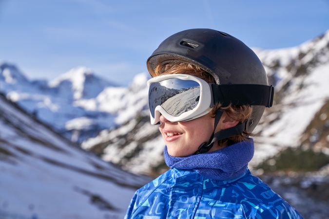 Glad boy looking away in snowy mountains